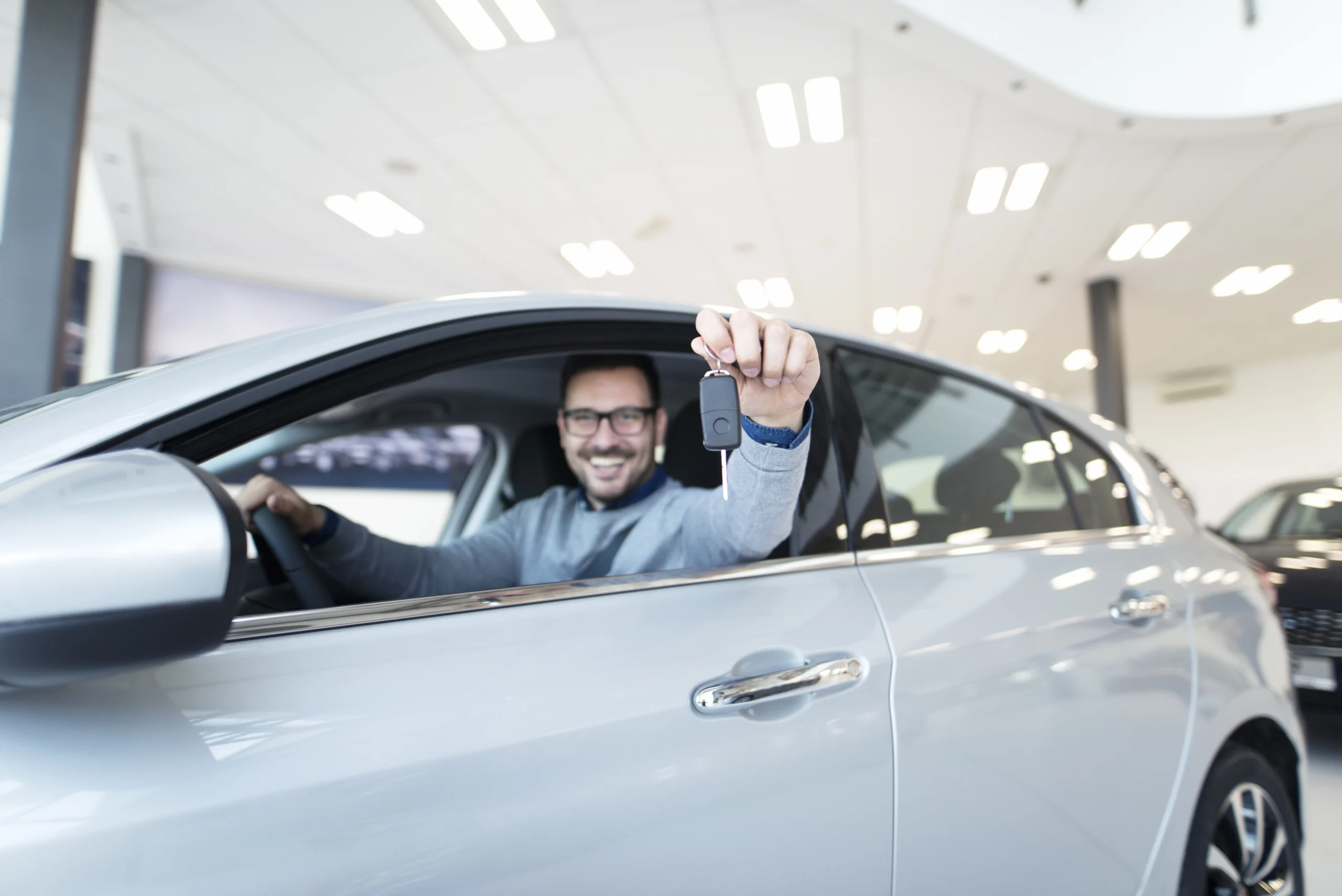 Homem feliz no seu carro que conseguiu comprar parcelado
